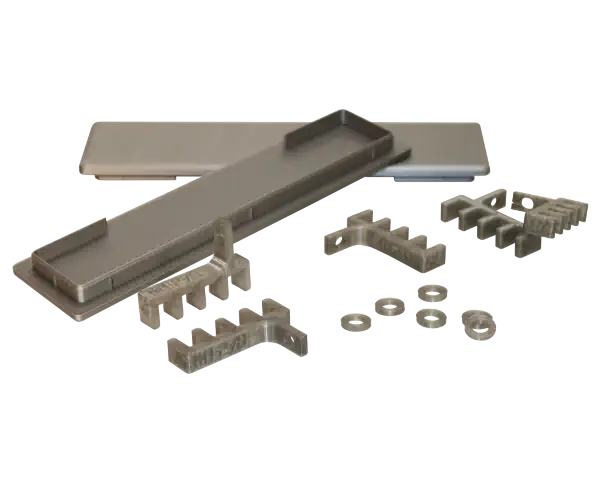 A group of fabricated parts which includes rectangular caps, horizontal machine gears, and washers
