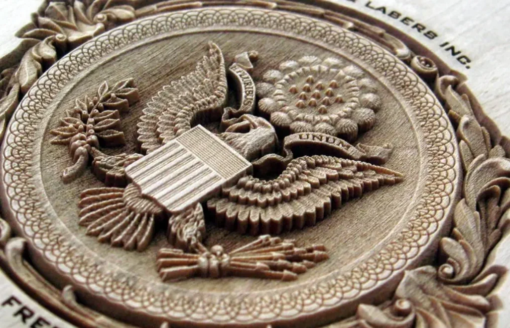 An engraved united states emblem with eagle and shield and baroque design in a circle on wood